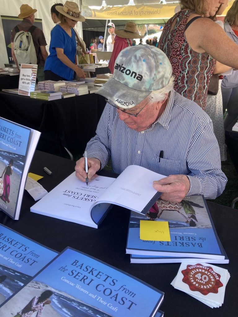 A University of Arizona Press authors seated at a table, signing books.
