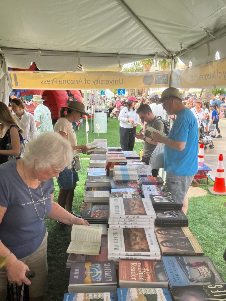 People gather around a table of books and browse at the Tucson Festival of Books.