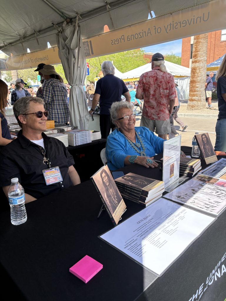 Two University of Arizona Press authors seated at a table to sign books.