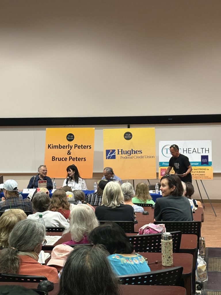 A crowded lecture hall with 4 panelists seated at a table.