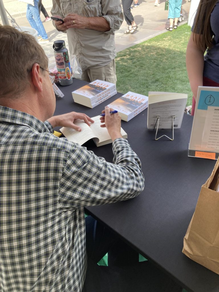 A University of Arizona Press authors seated at a table, signing books.